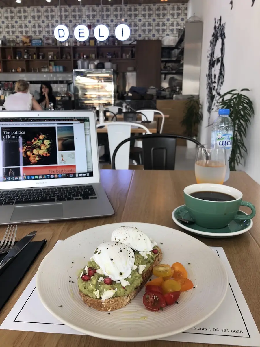 Avocado toast and coffee next to a laptop at Autograph Deli